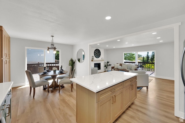 10852 S Starpine Dr, Sandy, UT 84094 - kitchen featuring light wood-style floors, open floor plan, a center island, recessed lighting, and a glass covered fireplace
