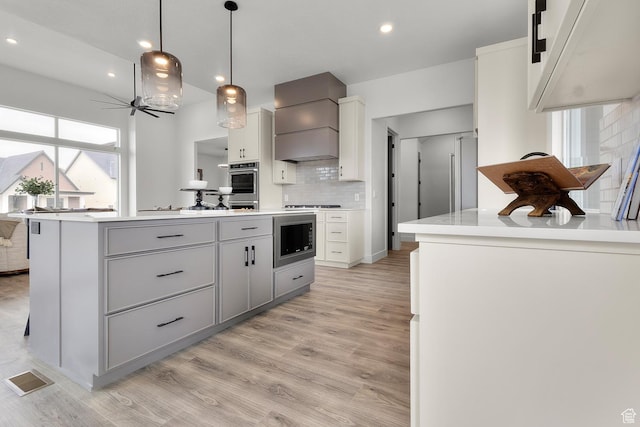 4269 N Maple Hollow Dr Unit 117, Lehi, UT 84043 - kitchen with custom range hood, built in microwave, gray cabinets, backsplash, and light countertops