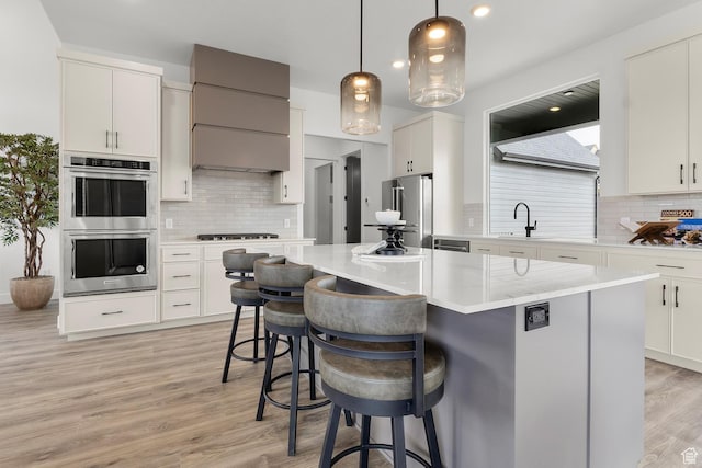 4269 N Maple Hollow Dr Unit 117, Lehi, UT 84043 - kitchen featuring appliances with stainless steel finishes, decorative backsplash, a breakfast bar, light wood-style floors, and a kitchen island