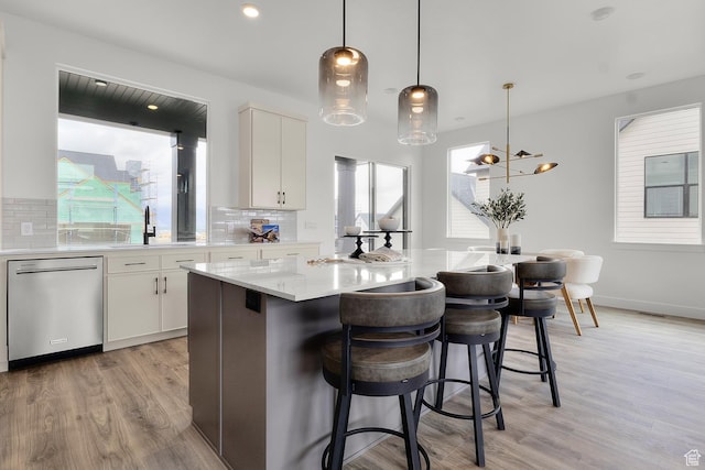 4269 N Maple Hollow Dr Unit 117, Lehi, UT 84043 - kitchen featuring stainless steel dishwasher, light wood finished floors, decorative backsplash, a kitchen island, and white cabinets