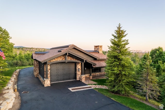 9156 E Forest Rd Unit 24, Heber City, UT 84032 - view of front facade with stone siding, driveway, a chimney, roof mounted solar panels, and a garage