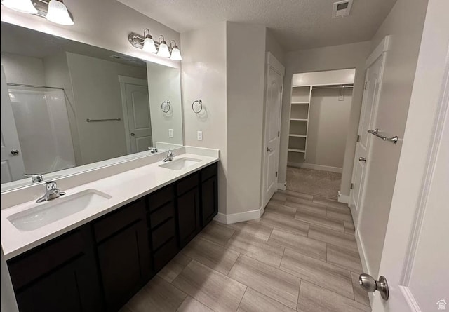 1738 W Terra Vis, Saratoga Springs, UT 84045 - bathroom featuring double vanity, a spacious closet, a textured ceiling, and a shower