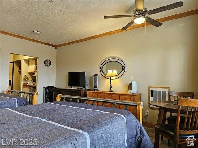 223 Hunter Ridge Rd Unit E121, Brian Head, UT 84719 - bedroom with crown molding, a textured ceiling, wood finished floors, and vaulted ceiling