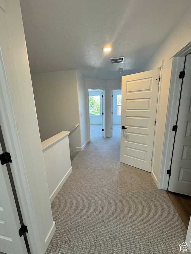 4687 S Roger View Ln Unit 8, West Valley City, UT 84119 - hallway featuring a textured ceiling, an upstairs landing, and carpet floors