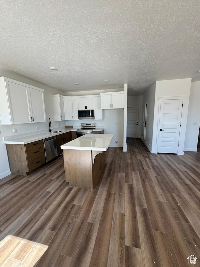 4687 S Roger View Ln Unit 8, West Valley City, UT 84119 - kitchen with stainless steel appliances, a center island, white cabinetry, dark wood-style flooring, and a textured ceiling