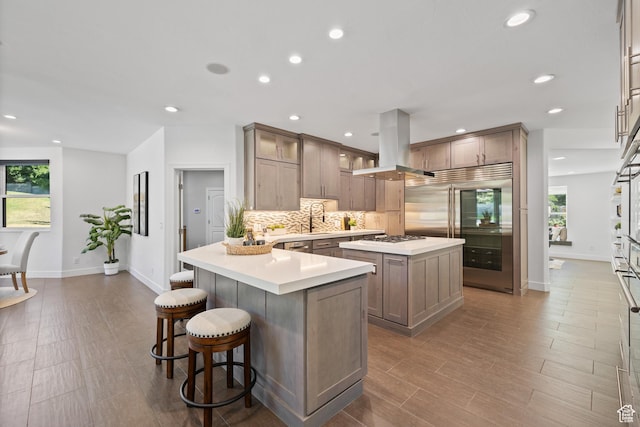 6273 S Oakcrest Cir, Holladay, UT 84121 - kitchen with built in fridge, island range hood, backsplash, a kitchen breakfast bar, and a kitchen island