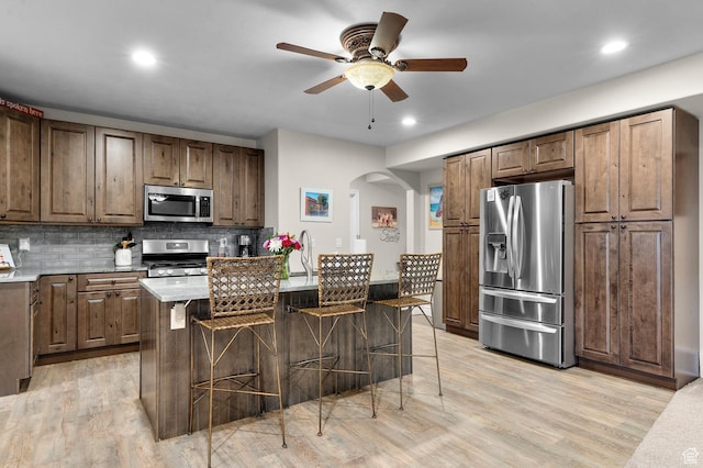 1524 E 330 N, Lehi, UT 84043 - kitchen with appliances with stainless steel finishes, ceiling fan, arched walkways, a kitchen bar, and decorative backsplash