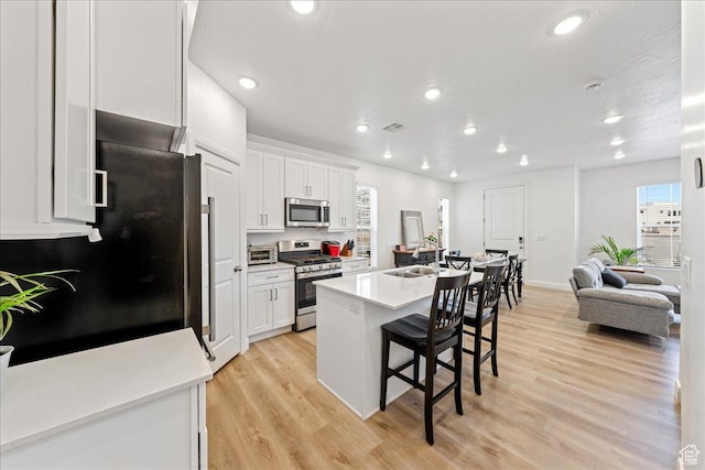 6029 S Carnelian Pkwy, St George, UT 84790 - kitchen featuring appliances with stainless steel finishes, a breakfast bar, light wood finished floors, white cabinetry, and recessed lighting