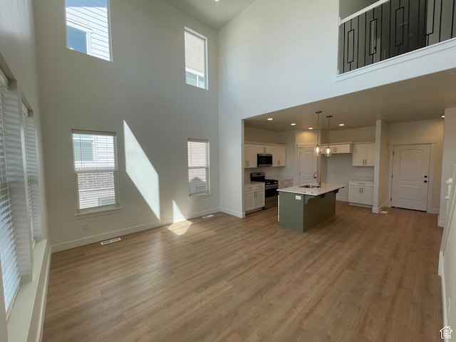 4332 W Watchmen Way, Herriman, UT 84096 - kitchen with stainless steel appliances, open floor plan, a high ceiling, white cabinets, and light wood finished floors