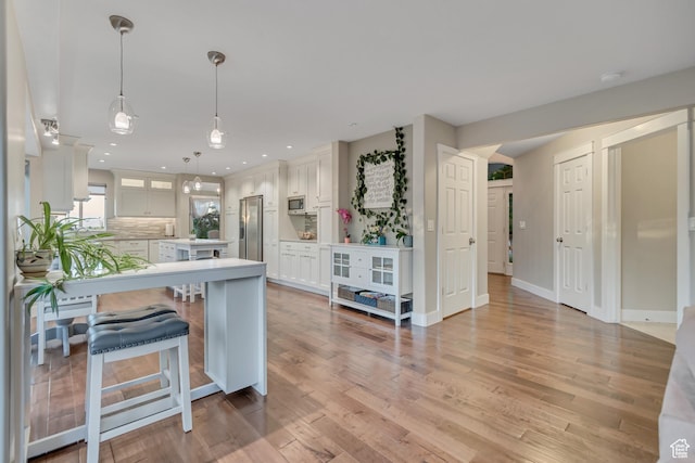 14012 S Osborne Ln E, Draper, UT 84020 - kitchen with appliances with stainless steel finishes, a breakfast bar, light countertops, light wood-style floors, and recessed lighting