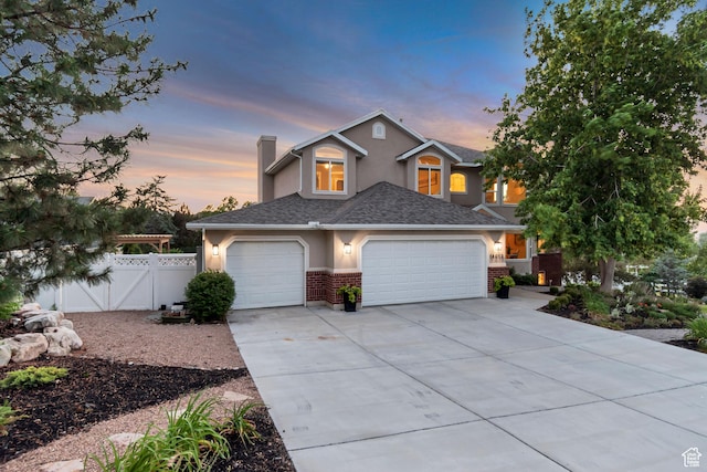 14012 S Osborne Ln E, Draper, UT 84020 - view of front facade with stucco siding, concrete driveway, a chimney, and brick siding