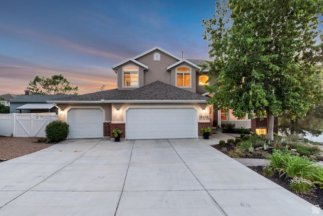 14012 S Osborne Ln E, Draper, UT 84020 - view of front of property featuring an attached garage, brick siding, concrete driveway, stucco siding, and a shingled roof