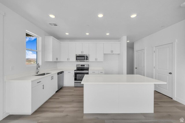 5599 S Carnelian Pkwy Unit 205, St George, UT 84790 - kitchen featuring stainless steel appliances, a center island, light wood-style flooring, white cabinetry, and light countertops