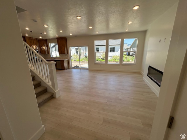 564 N 800 W, Smithfield, UT 84335 - unfurnished living room featuring recessed lighting, a glass covered fireplace, stairway, light wood-style flooring, and a textured ceiling
