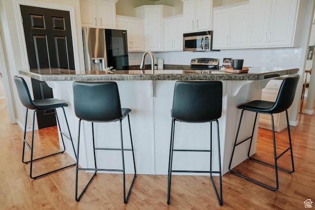 1628 E Lone Oak Dr, Draper, UT 84020 - kitchen featuring appliances with stainless steel finishes, a kitchen bar, light wood finished floors, and white cabinets