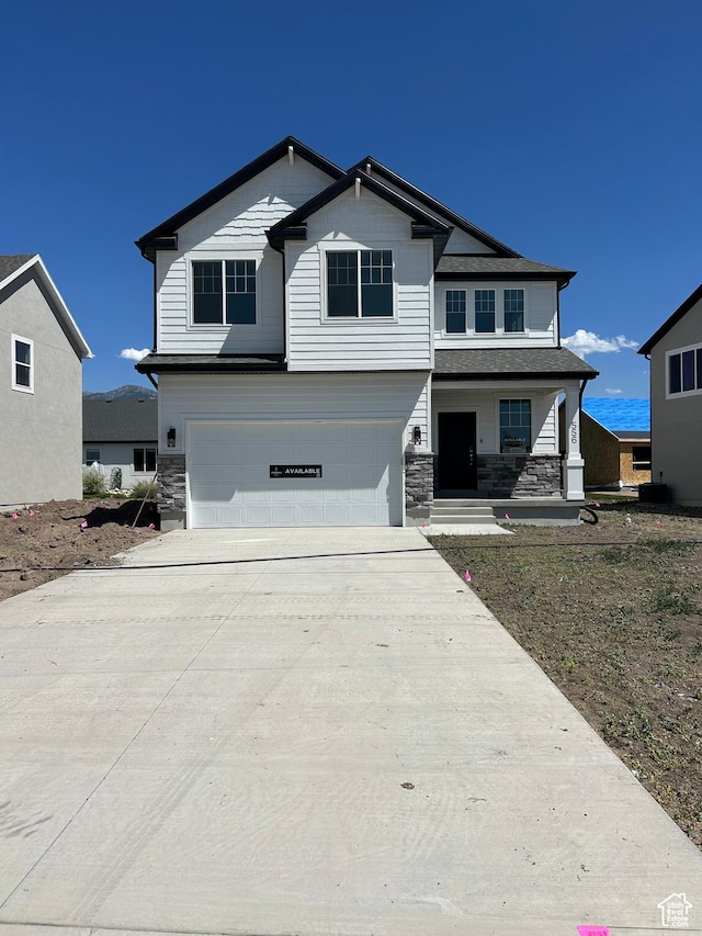 556 N 800 W, Smithfield, UT 84335 - view of front facade featuring an attached garage, stone siding, driveway, and covered porch