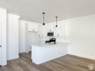 1805 N 70 W, Tooele, UT 84074 - kitchen featuring stainless steel microwave, dark wood finished floors, a peninsula, white cabinetry, and stove