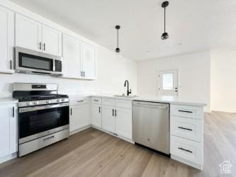 1805 N 70 W, Tooele, UT 84074 - kitchen with appliances with stainless steel finishes, a peninsula, light wood-style flooring, and light countertops