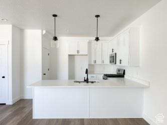 1805 N 70 W, Tooele, UT 84074 - kitchen with stainless steel microwave, range, wood finished floors, a peninsula, and white cabinetry