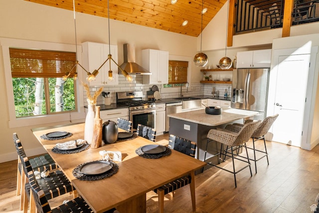 2143 S Aspen Cir, Wanship, UT 84017 - kitchen with stainless steel appliances, wall chimney exhaust hood, tasteful backsplash, open shelves, and light wood finished floors