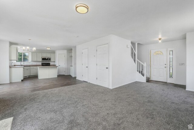 4004 N Shelter Cv W, Lehi, UT 84043 - unfurnished living room featuring dark colored carpet, stairway, a chandelier, and dark wood finished floors