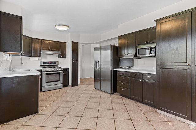 2124 W 7125 S, West Jordan, UT 84084 - kitchen with appliances with stainless steel finishes, under cabinet range hood, dark brown cabinetry, light countertops, and light tile patterned floors