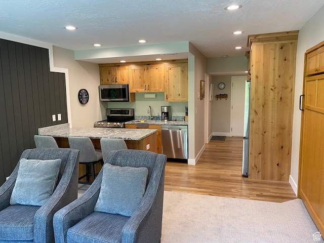 9202 E Lodge Dr Unit 201202, Snowbird, UT 84092 - kitchen featuring appliances with stainless steel finishes, light wood-style floors, open floor plan, recessed lighting, and light stone counters