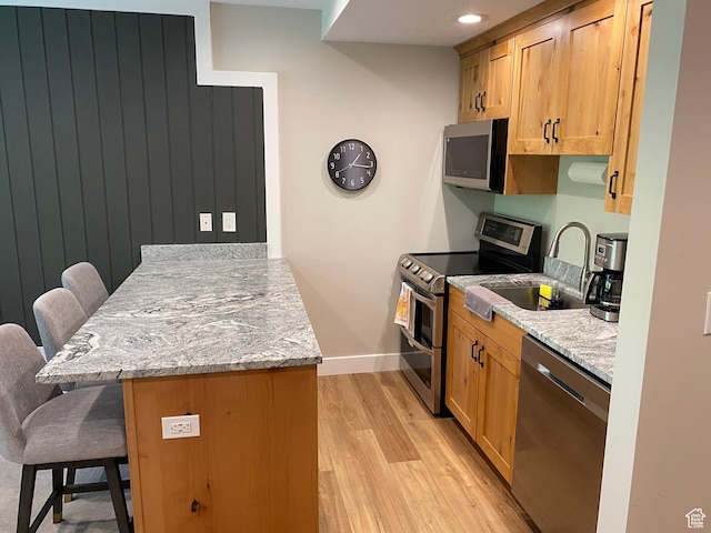 9202 E Lodge Dr Unit 201202, Snowbird, UT 84092 - kitchen with stainless steel appliances, a peninsula, a kitchen breakfast bar, light wood-style flooring, and light stone countertops