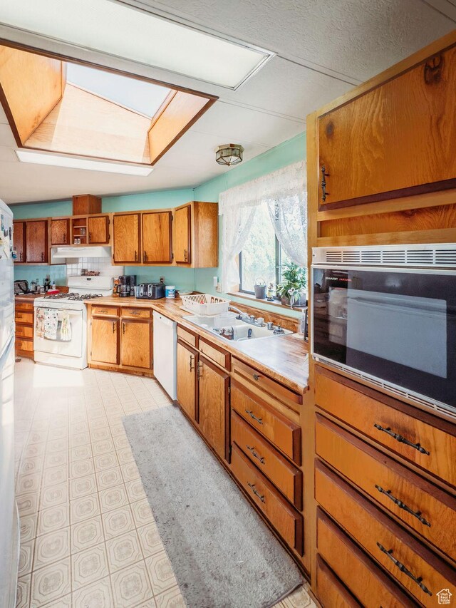 1633 W 2100 N, Helper, UT 84526 - kitchen with white appliances, a skylight, brown cabinets, under cabinet range hood, and light countertops