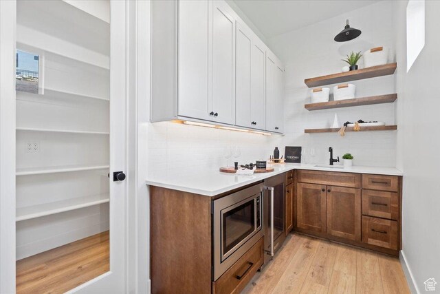 5554 N Fox Canyon Rd, Lehi, UT 84043 - indoor wet bar with stainless steel microwave, light wood-style floors, tasteful backsplash, and beverage cooler