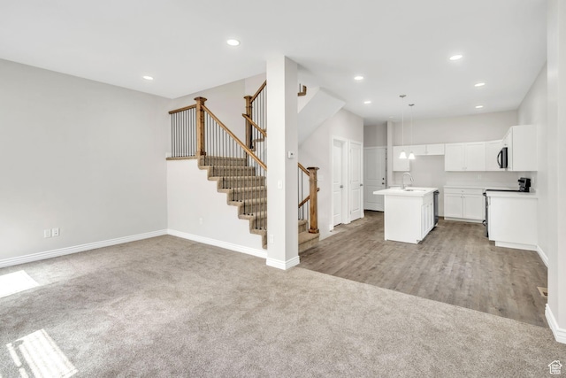 3872 S 1630 W, West Valley City, UT 84119 - kitchen featuring light carpet, open floor plan, an island with sink, stainless steel microwave, and white cabinetry