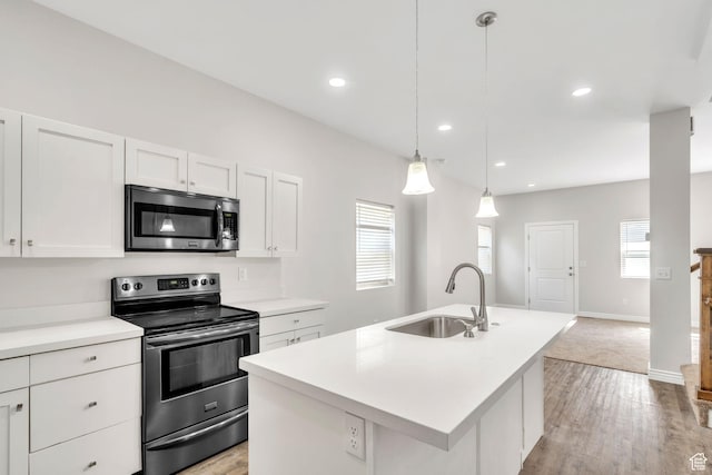 3872 S 1630 W, West Valley City, UT 84119 - kitchen with stainless steel appliances, a kitchen island with sink, light countertops, white cabinets, and light wood-style flooring
