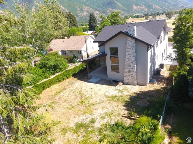 435 E Maple St, Mapleton, UT 84664 - rear view of house with stone siding, stucco siding, a chimney, and a mountain view