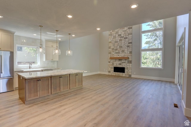 435 E Maple St, Mapleton, UT 84664 - kitchen with freestanding refrigerator, a kitchen island, light wood finished floors, backsplash, and open floor plan