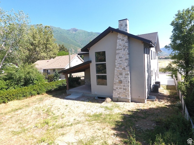 435 E Maple St, Mapleton, UT 84664 - rear view of property with stone siding, stucco siding, a chimney, and a mountain view