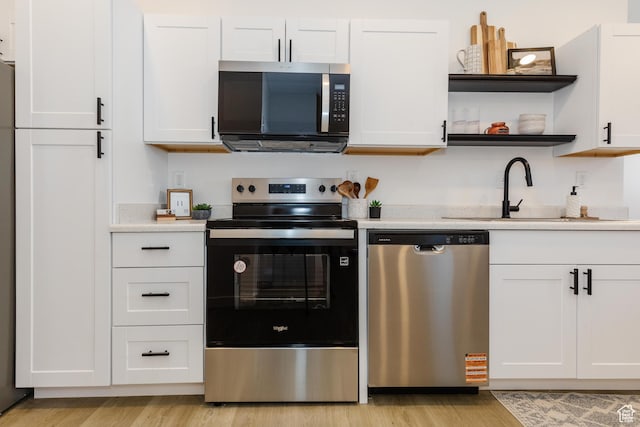 221 E 8th S, Ogden, UT 84401 - kitchen with stainless steel appliances, light wood finished floors, light countertops, open shelves, and white cabinetry