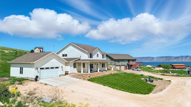 689 W Dee Dr, Garden City, UT 84028 - view of front of house featuring driveway, a porch, a garage, a front lawn, and a water and mountain view