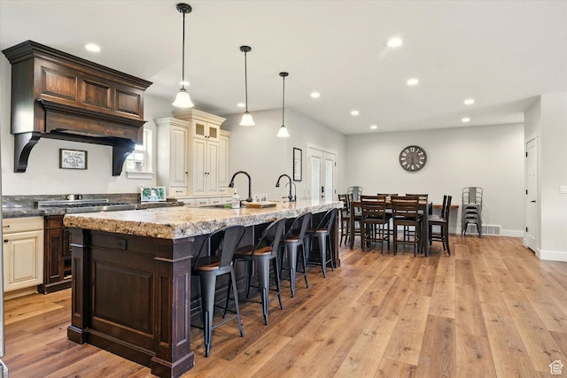 689 W Dee Dr, Garden City, UT 84028 - kitchen featuring light stone countertops, recessed lighting, a large island, a breakfast bar area, and cream cabinets