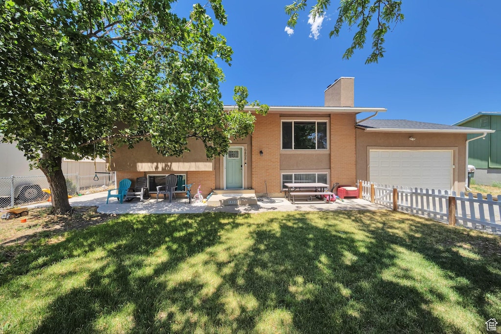 6498 W Castle View Dr S, West Valley City, UT 84128 - rear view of property with a chimney, an attached garage, brick siding, and a patio
