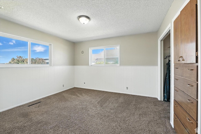 572 W 300 N, Hyrum, UT 84319 - unfurnished bedroom with a wainscoted wall, a textured ceiling, and dark carpet