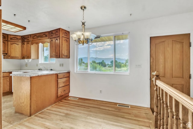 185 S 200 W, Providence, UT 84332 - kitchen with a chandelier, brown cabinetry, light countertops, light wood-type flooring, and decorative light fixtures