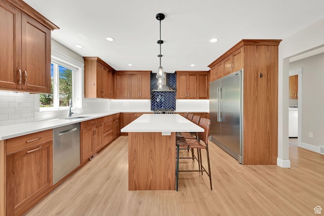 6699 E 950 S, Huntsville, UT 84317 - kitchen with appliances with stainless steel finishes, washer / dryer, wall chimney exhaust hood, a kitchen breakfast bar, and light wood-style floors
