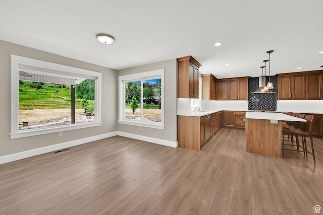 6699 E 950 S, Huntsville, UT 84317 - kitchen featuring light countertops, a kitchen breakfast bar, stainless steel dishwasher, decorative backsplash, and light wood-style flooring