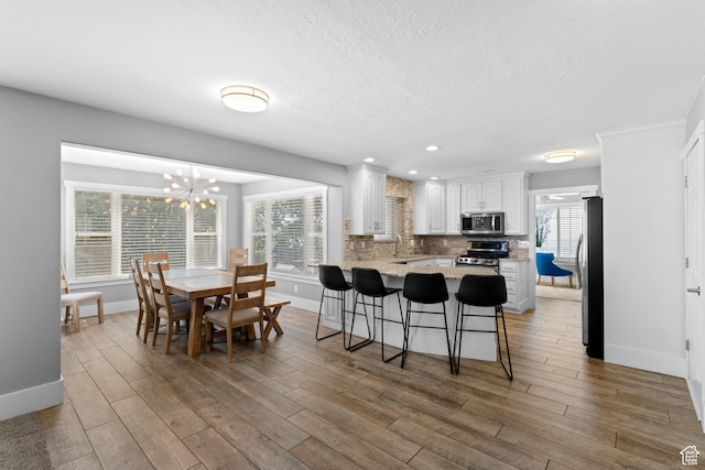 1060 E 1100 N, Pleasant Grove, UT 84062 - kitchen with appliances with stainless steel finishes, a peninsula, white cabinets, a breakfast bar, and light wood-style flooring