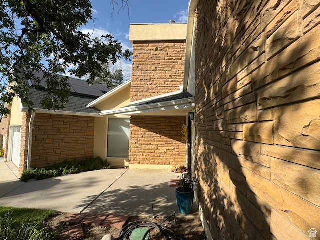 8463 S Jackson Hole Dr E, Sandy, UT 84093 - view of home's exterior with solar panels, a shingled roof, stucco siding, and brick siding