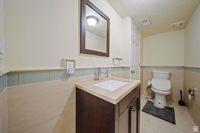 8463 S Jackson Hole Dr E, Sandy, UT 84093 - bathroom with tile patterned flooring, vanity, a textured ceiling, wainscoting, and tile walls