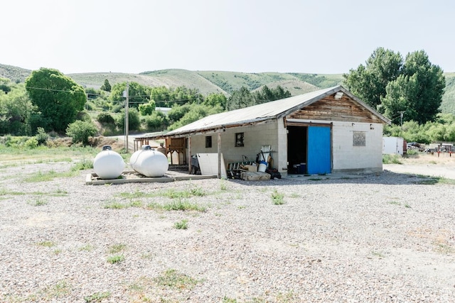 3229 E Riverdale Rd, Preston, ID 83263 - rear view of house featuring concrete block siding, an outdoor structure, and a mountain view