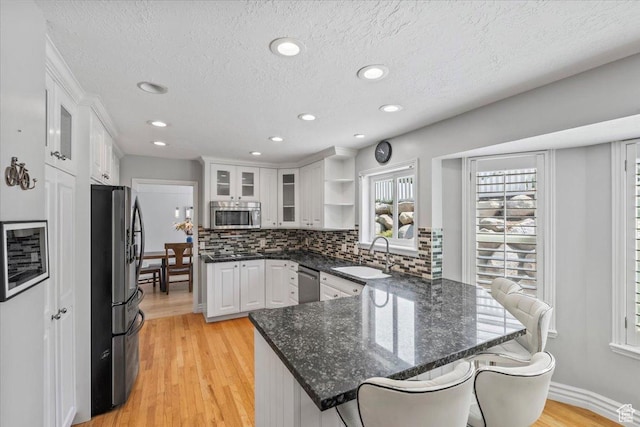 4104 S Bridlewood Dr E, Bountiful, UT 84010 - kitchen featuring stainless steel appliances, a peninsula, white cabinets, a breakfast bar area, and decorative backsplash