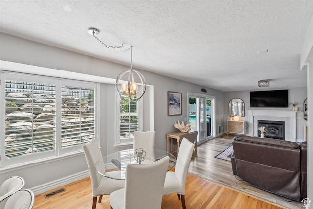 4104 S Bridlewood Dr E, Bountiful, UT 84010 - dining space featuring a textured ceiling, plenty of natural light, a chandelier, light wood finished floors, and a fireplace