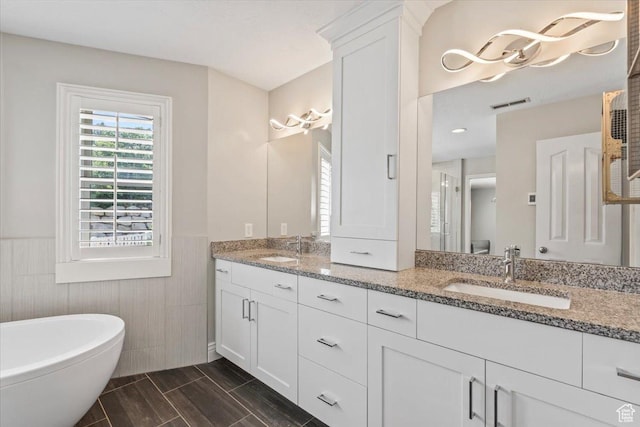 4104 S Bridlewood Dr E, Bountiful, UT 84010 - bathroom with wainscoting, double vanity, a freestanding tub, tile walls, and wood finished floors